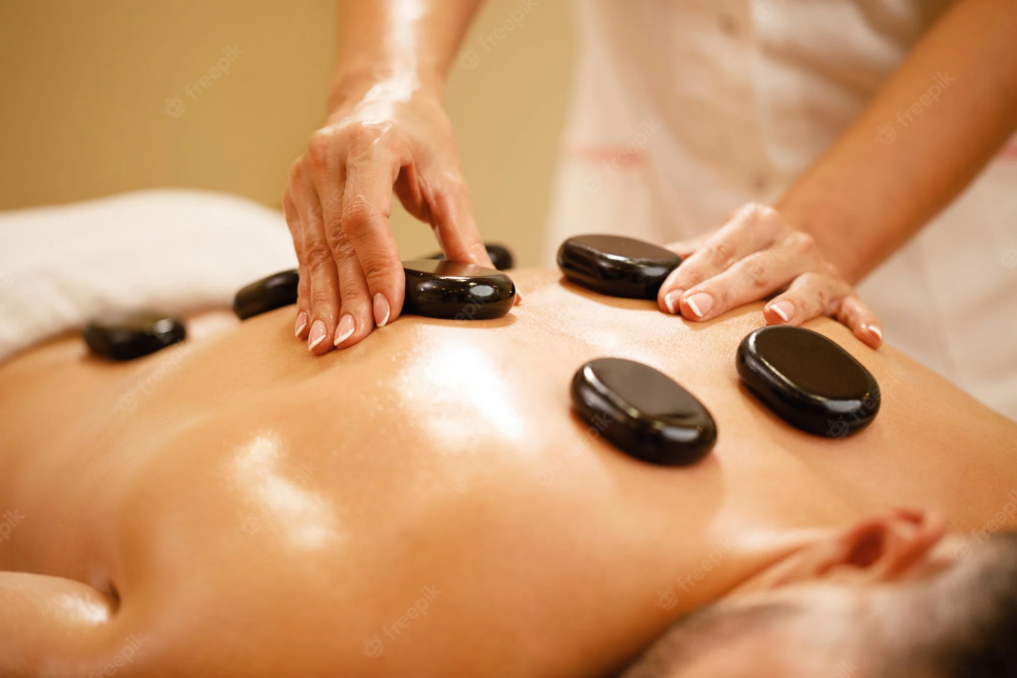 closeup-therapists-placing-hot-stones-man-s-back-during-lastone-therapy-spa_637285-2243